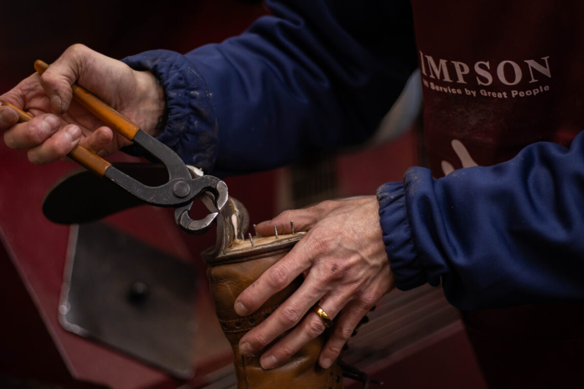 Man with pliers taking the heel off a shoe